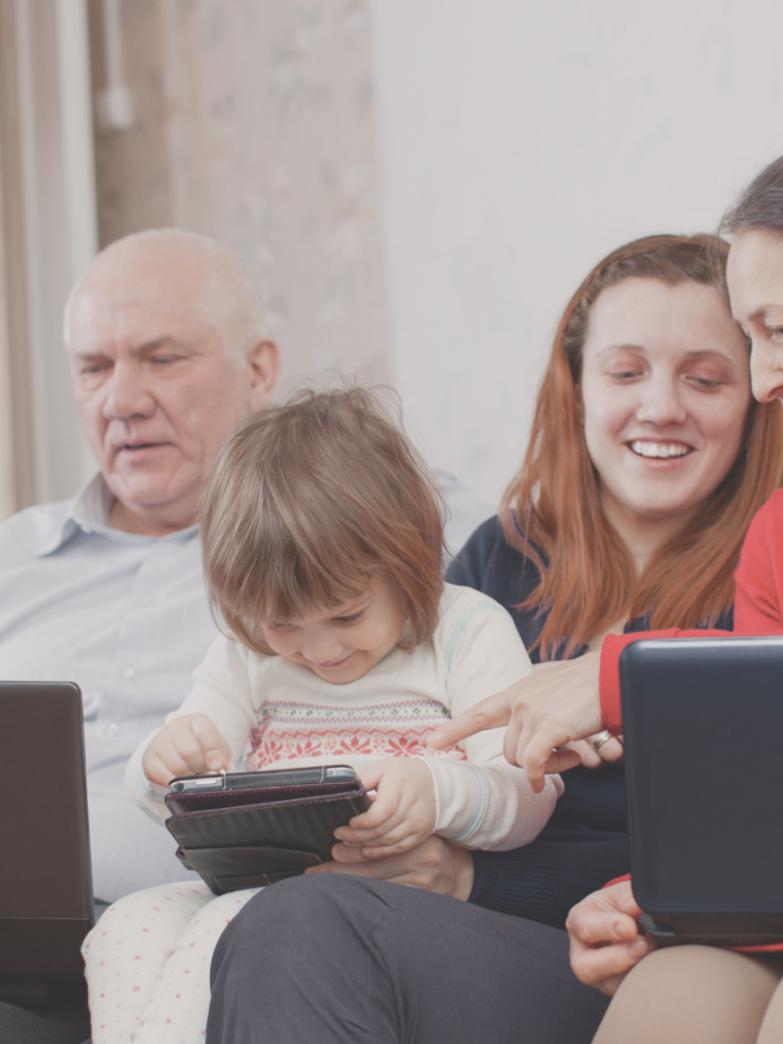 Des membres d'une famille multigénérationnelle utilisent des ordinateurs portables et des tablettes.