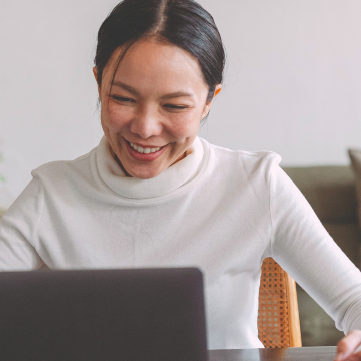 Une femme souriante travaille sur son ordinateur portable.