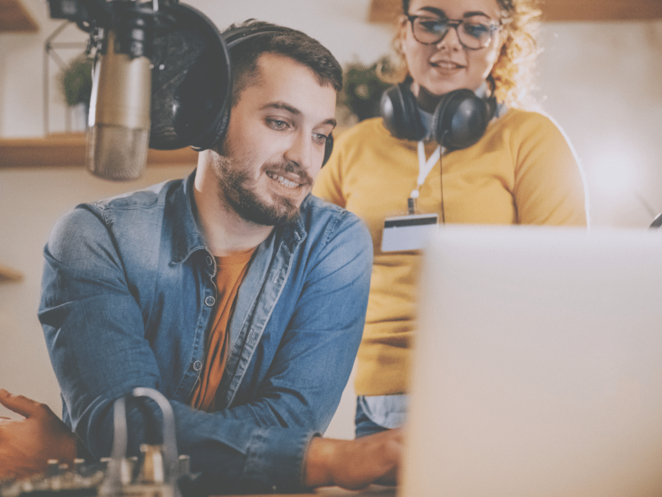 Deux animateurs radio travaillent sur leur ordinateur dans leur studio.