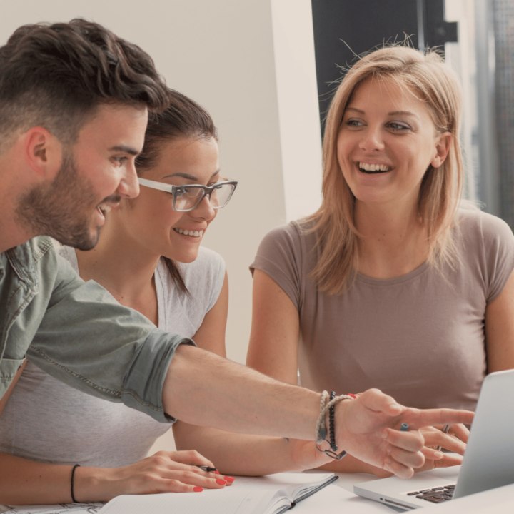 Trois collègues discutent devant un ordinateur.