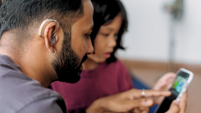 Un papa malentendant aide sa fille à s'exercer sur Projet Voltaire avec son téléphone portable.