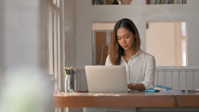 Une femme travaille sur son ordinateur chez elle.