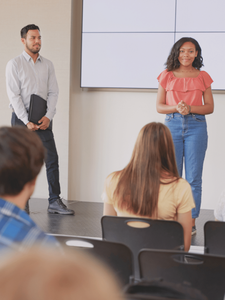 Une élève fait une présentation devant sa classe et son professeur.