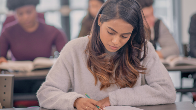 Une étudiante prend des notes en cours.