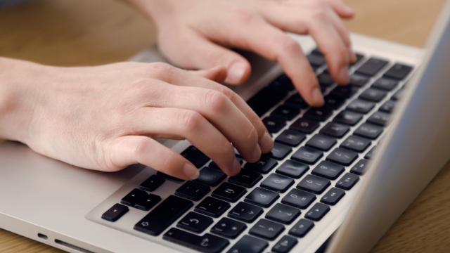 Des mains tapent sur un clavier d'ordinateur.