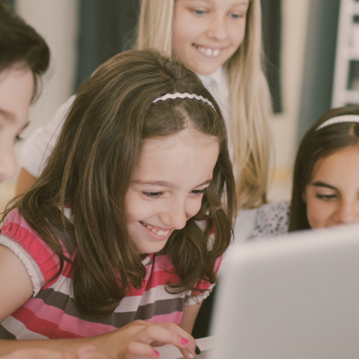 Quatre enfants s'amusent sur un ordinateur.