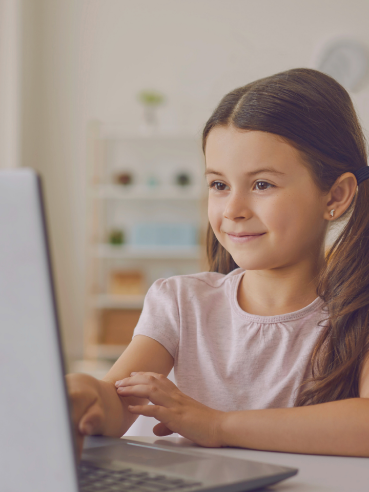 Une élève de primaire étudie sur un ordinateur portable à la maison.
