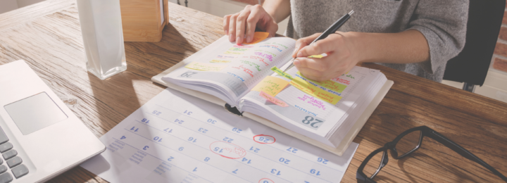 Des mains féminines écrivent dans un agenda.