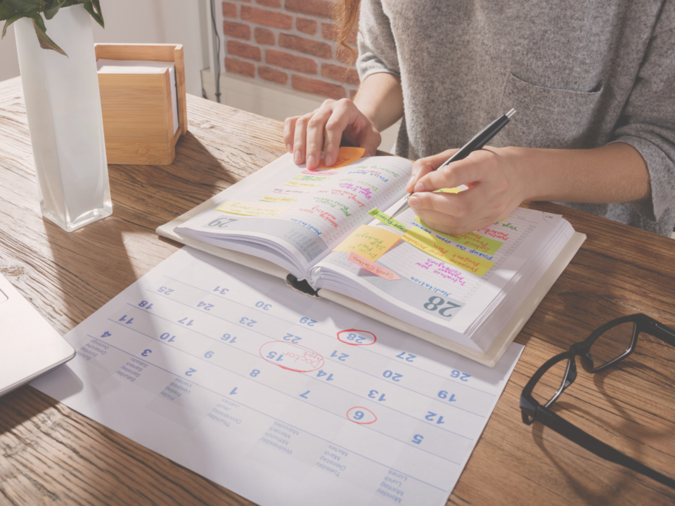 Des mains féminines écrivent dans un agenda.