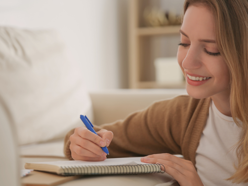 Une femme écrit une lettre en souriant.