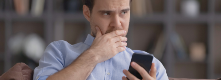 Un homme hésite en regardant son téléphone.