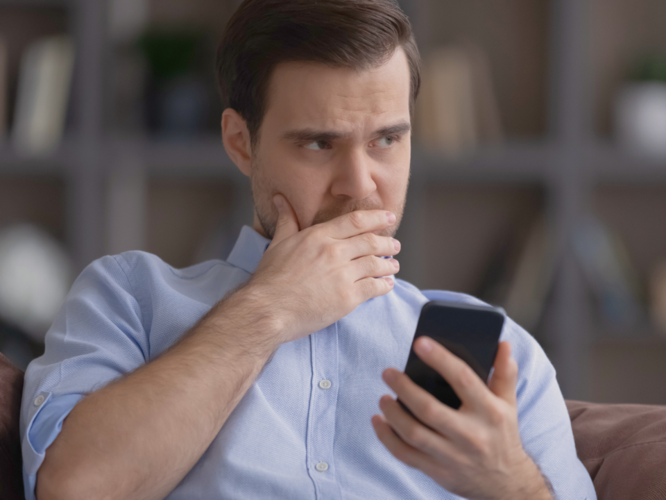 Un homme hésite en regardant son téléphone.