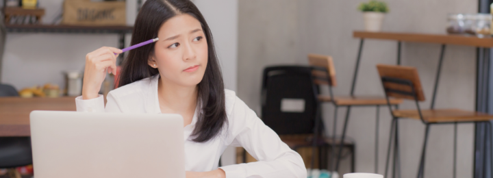 Une femme réfléchit devant son ordinateur portable.