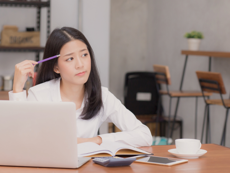 Une femme réfléchit devant son ordinateur portable.