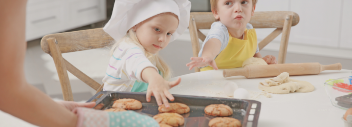Des enfants tendent les bras pour manger des biscuits tout juste sortis du four.