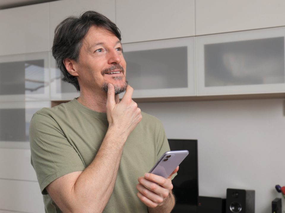 Un homme réfléchit sur son téléphone portable.