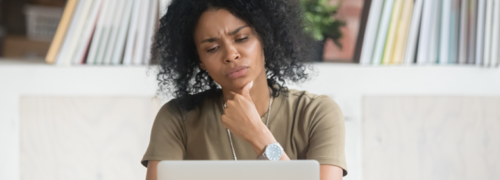 Une femme réfléchit devant son ordinateur portable.