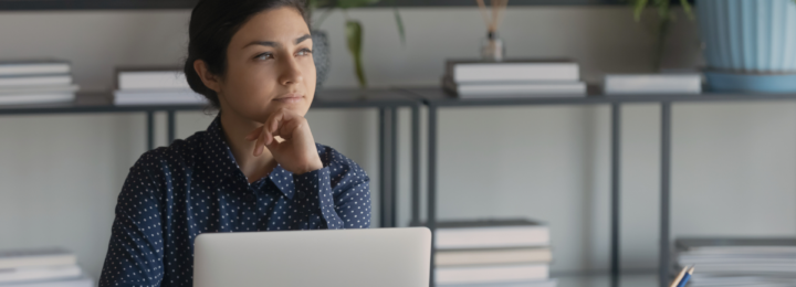 Une femme réfléchit devant son ordinateur portable.