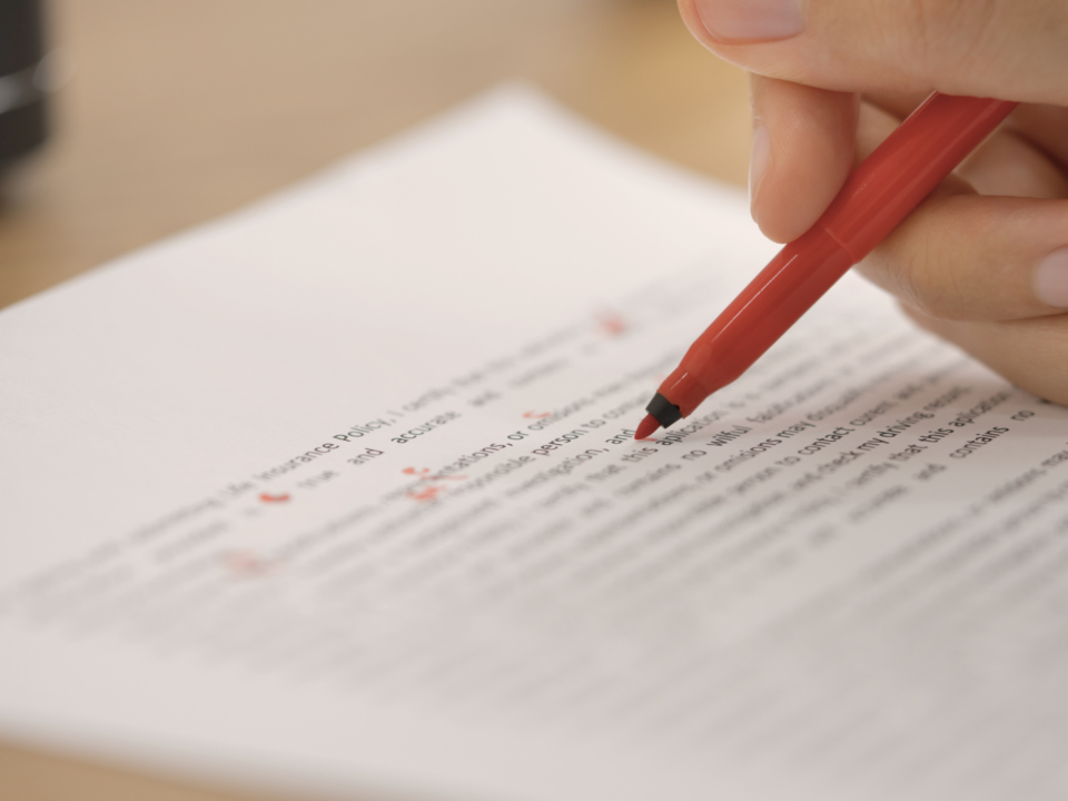 Une personne corrige un texte au stylo rouge.