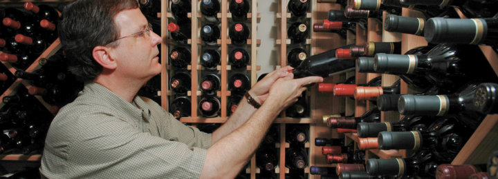 Un homme trie des bouteilles de vin dans sa cave.