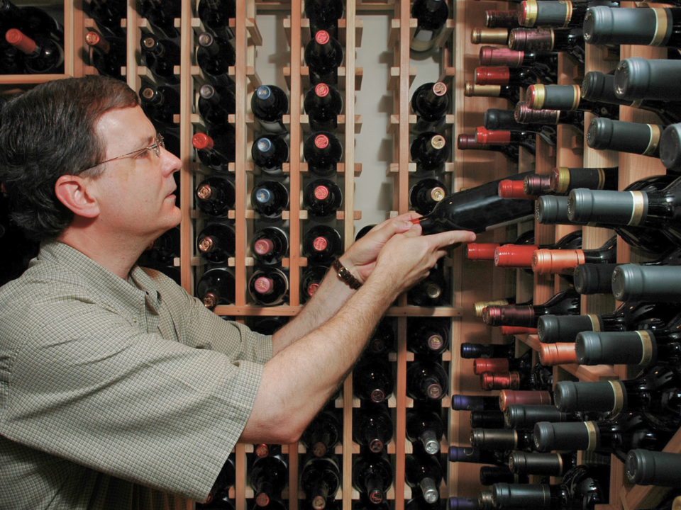 Un homme trie des bouteilles de vin dans sa cave.