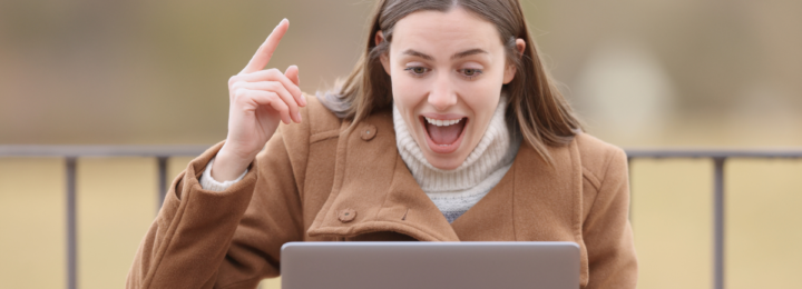 Une femme est surprise, index en l'air devant son ordinateur.