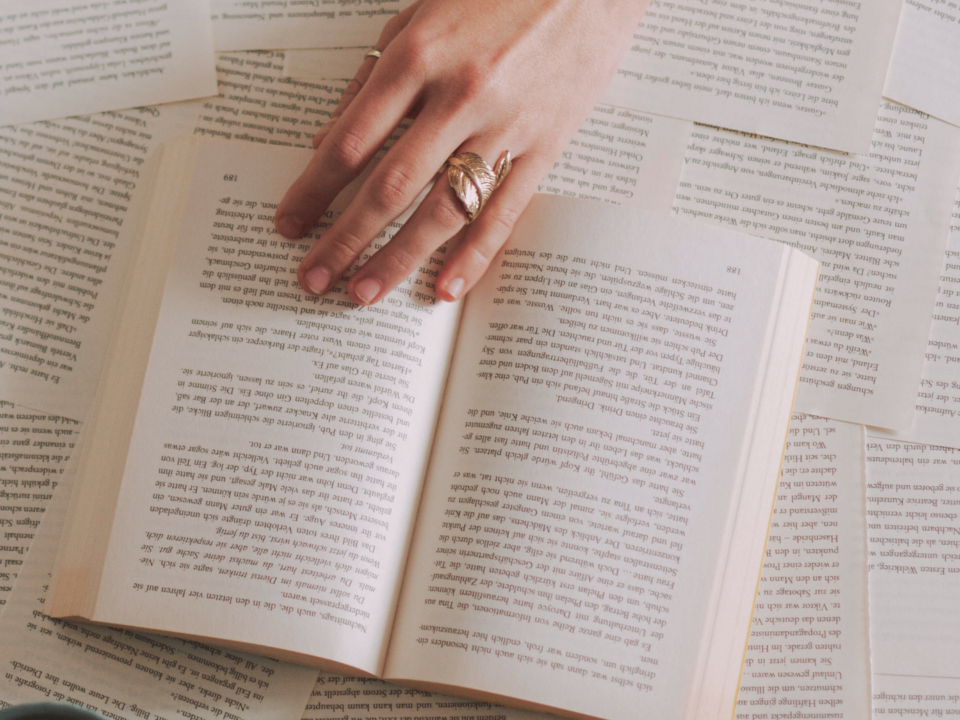 Une main féminine tourne les pages d'un livre.