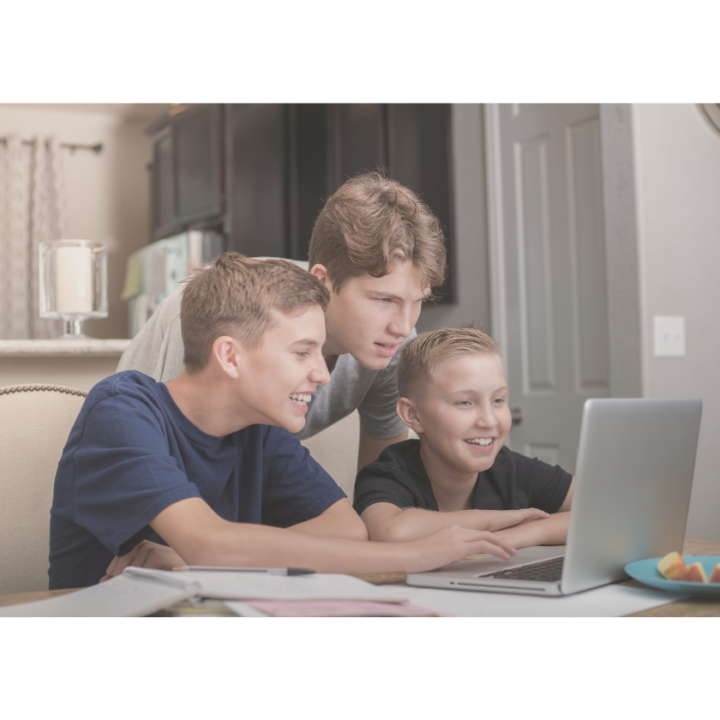 Trois jeunes garçons travaillent sur un ordinateur portable chez eux.