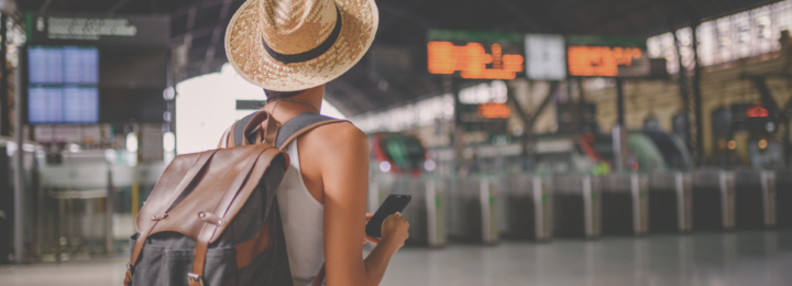 Une femme regarde des panneaux dans une gare.
