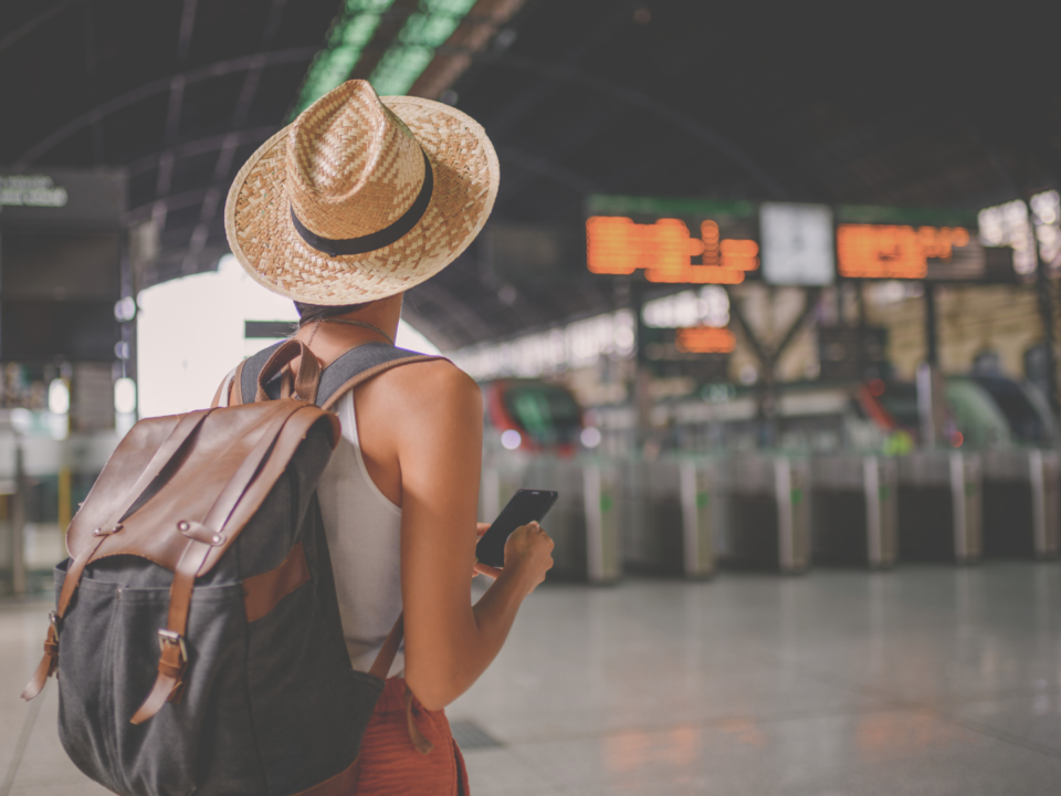 Une femme regarde des panneaux dans une gare.