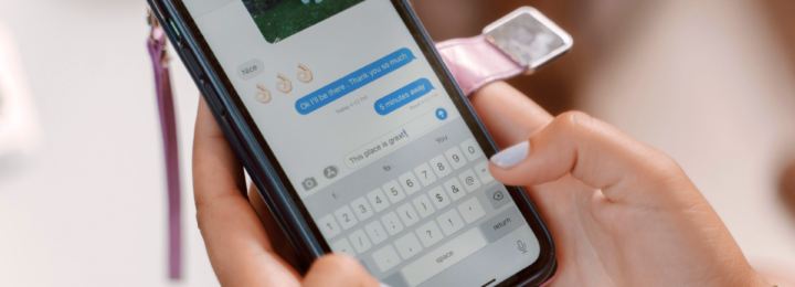 Des mains féminines tapent un message sur un téléphone.