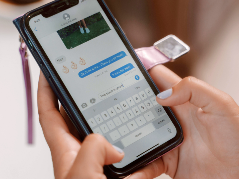 Des mains féminines tapent un message sur un téléphone.
