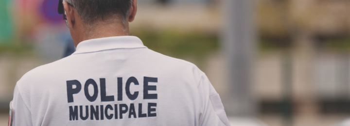 Un policier marche dans la rue, de dos.