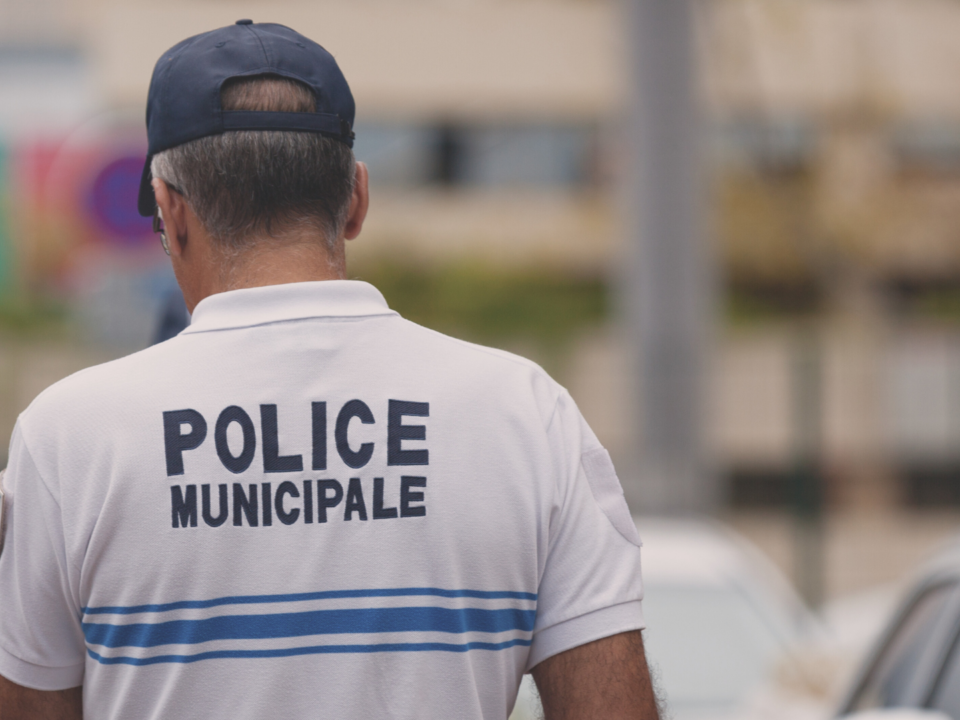 Un policier marche dans la rue, de dos.