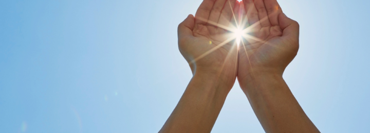 Une personne laisse passer un rayon de soleil entre ses mains.