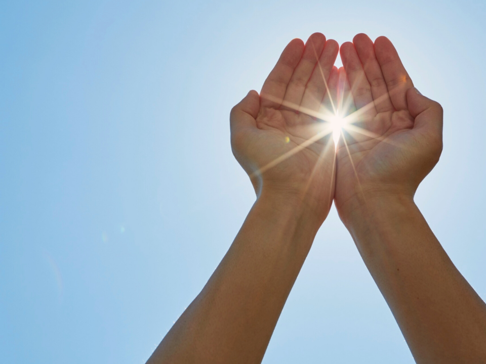 Une personne laisse passer un rayon de soleil entre ses mains.