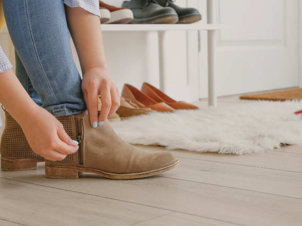 Une femme met ses bottines et ferme un zip.