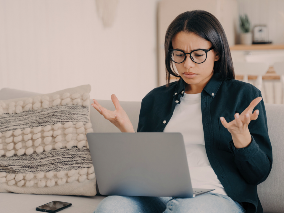 Une femme est perplexe devant son ordinateur portable.