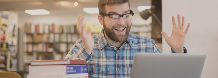 Un homme surpris travaille sur son ordinateur dans une bibliothèque.