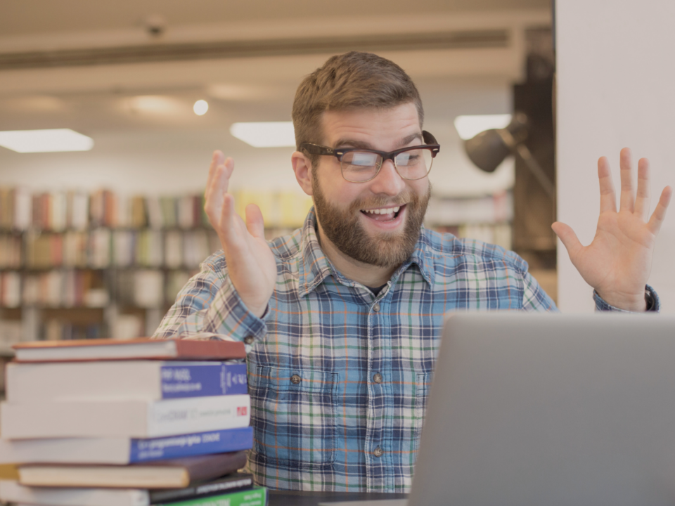 Un homme surpris travaille sur son ordinateur dans une bibliothèque.