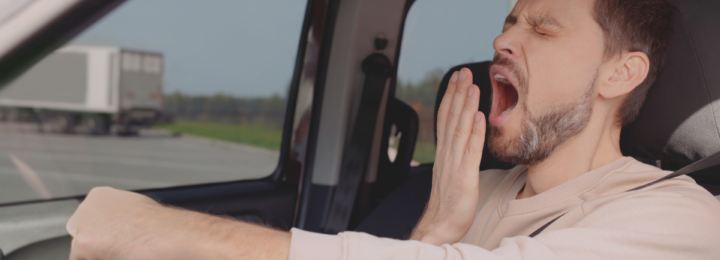 Un homme bâille dans sa voiture.