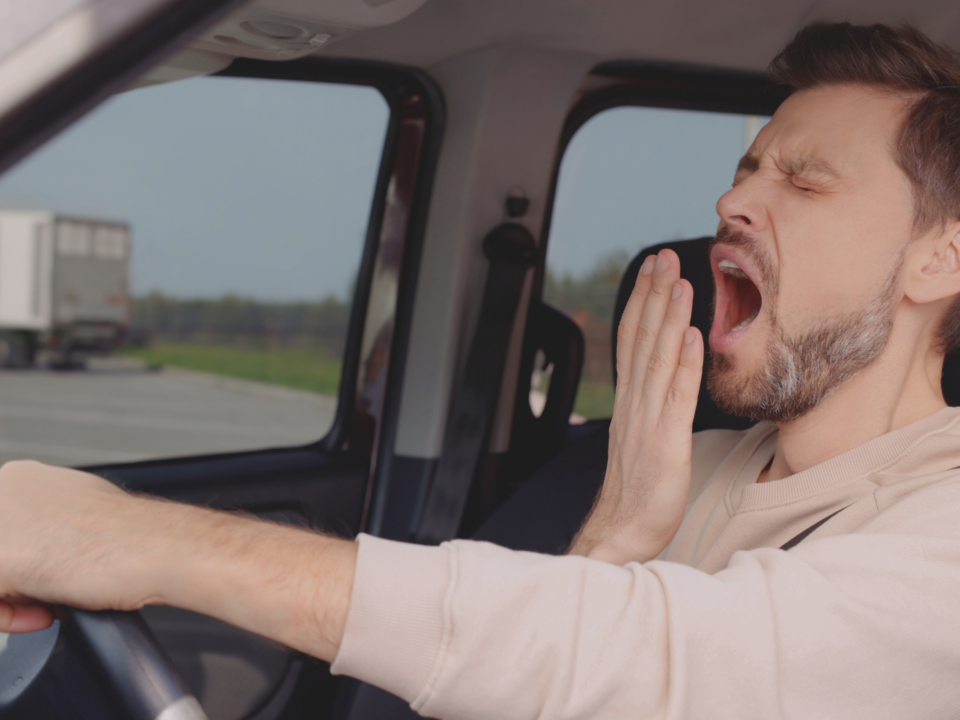 Un homme bâille dans sa voiture.
