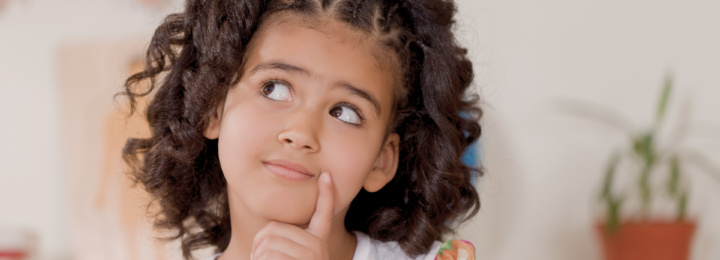Une petite fille réfléchit de manière malicieuse.