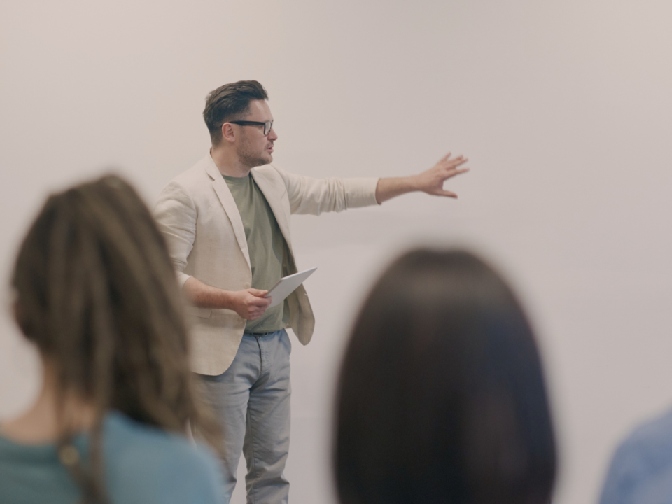 Un homme fait une présentation devant plusieurs personnes.