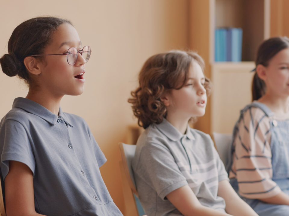 Trois enfants s'entraînent au chant.
