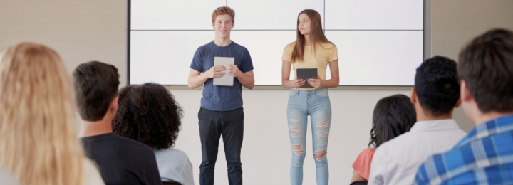 Deux lycéens font une présentation orale devant un public.
