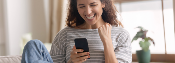 Une femme sur son téléphone portable, fait un signe de victoire.