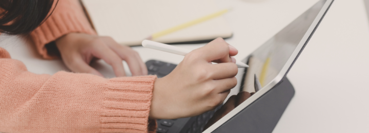 Des mains féminines écrivent sur une tablette.