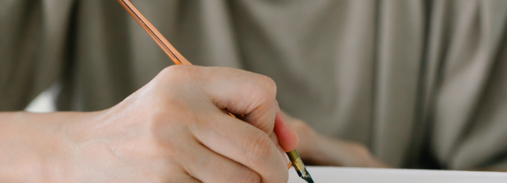 Une main masculine écrit une lettre à l'aide d'un stylo plume.