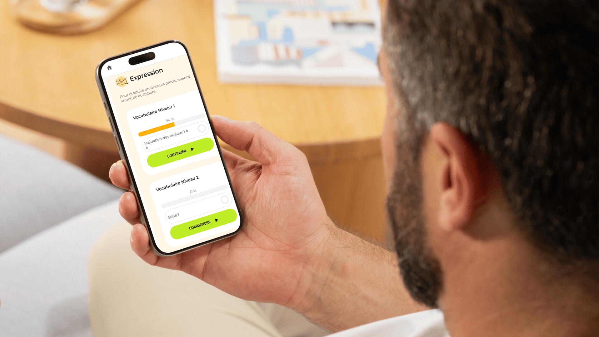 Un homme consulte un module d'expression écrite sur l'application Projet Voltaire, affiché sur l'écran de son smartphone.